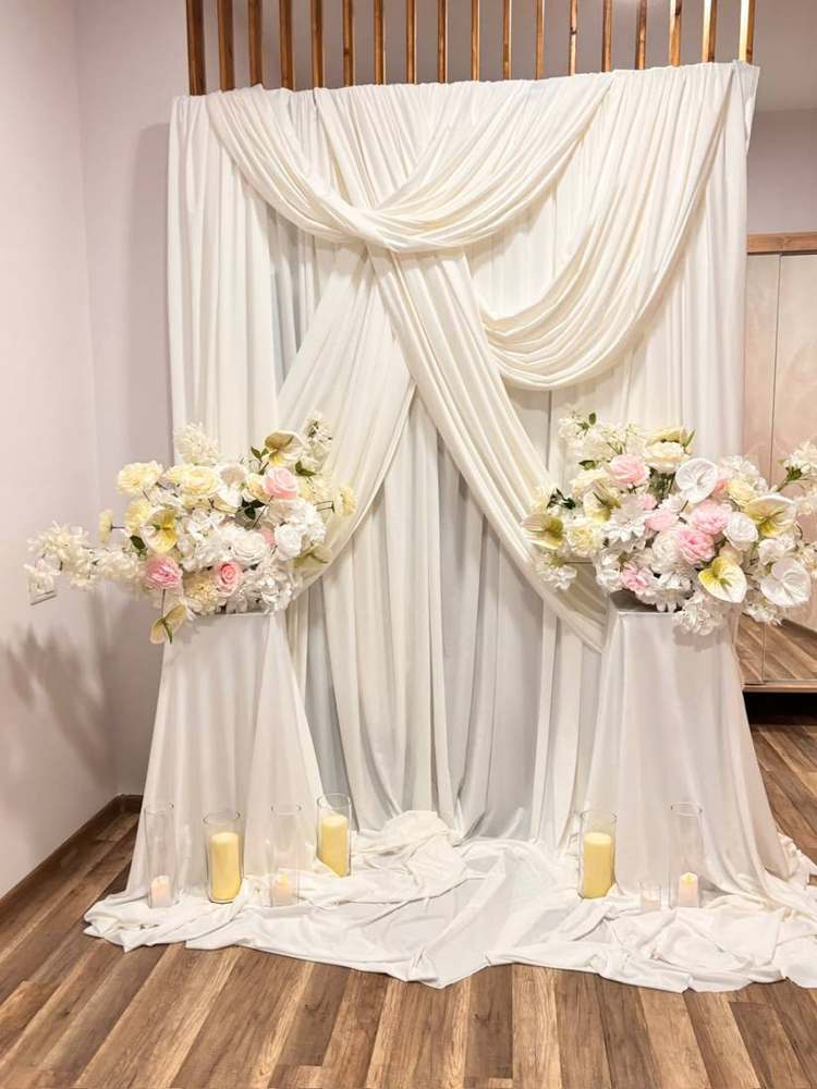 Decor elegant cu draperii albe și aranjamente florale pentru nuntă